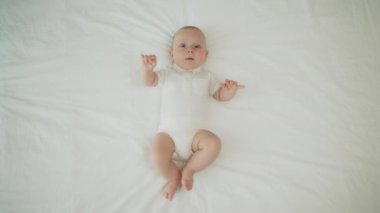 Top view of the newborn baby is lying on a white bed and blanket comfortable and safety. Carefree healthy babyhood, healthcare and paediatrics care concept