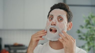 The person, applying a rejuvenating cosmetic mask to the face and with surprise and grimaces, having fun, enjoying himself. People and skincare concept