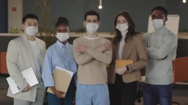 Portraits of business multicultural group standing at office with crossed arms wearing medical masks in order to protect themselves from coronavirus. Business, pandemic and health care concept