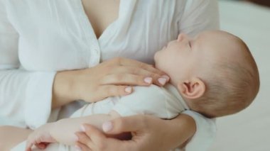 Side view of the mother holding her newborn baby while she sleeping peacefully feeling safe on mothers hands. Motherhood concept