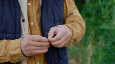 Close up of the mens hands catch the weight on the hook before casting the fishing rod. Fisherman equip a fishing rod in front of a fisherman. People and fishing concept