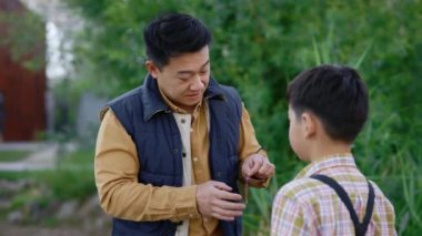 Close view of the asian father teaches son the subtleties of fishing before fishing. Dad shows his son how to change the bait into the hook. Family relationships and fishing concept