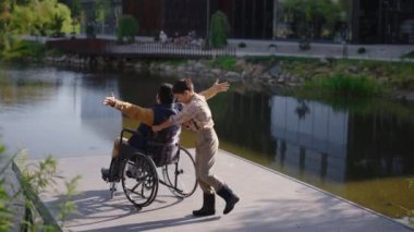 Disabled asian father having fun with his son near lake. Rehabilitation. Happy family fun spending time together. Fathers day.