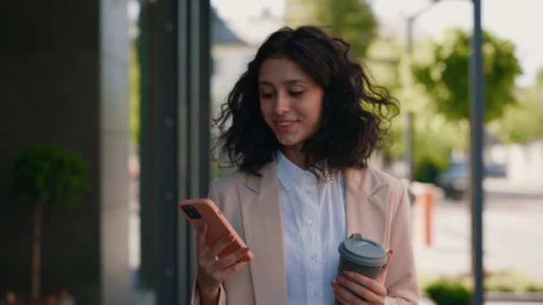 Drukke Glimlachende Zakenvrouw Loopt Met Koffie Naar Kantoor Met Smartphone — Stockvideo