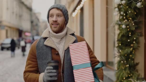남자가 크리스마스 선물을 모자와 스카프를 장식된 거리를 있습니다 사람들 — 비디오