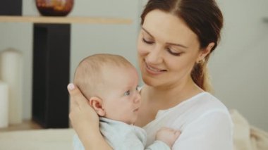 Yeni doğmuş bebeğini kucağında tutan ve modern kıyafetler giyen mutlu beyaz annenin portresi. Annelik kavramı