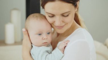 Yeni doğmuş bebeğini yeni dairesinde gözleri kapalı tutan gülümseyen beyaz annenin yakın görüntüsü. Annelik kavramı