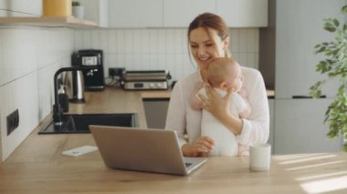 Happy gülümseyen beyaz bir anne yeni doğmuş bebeği kucağına alıp ailesiyle ya da arkadaşlarıyla görüntülü görüşme yaptı ve bebeğini gösterip onlarla konuştu. Teknoloji ve annelik kavramı