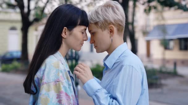 两个女同志站在市中心 一个舞伴吻着她的女朋友的额头 同性恋夫妇感到彼此相爱 浪漫的约会 — 图库视频影像