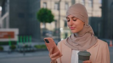 Ara verdiğinde tesettürlü, tesettürlü Arap bir iş kadını akıllı telefon kullanarak arkadaşlarıyla mesajlaşıyordu. İnsanlar ve teknoloji sektörü konsepti.