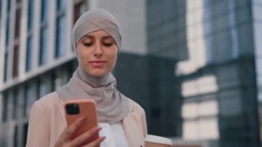 Gülümseyen iş kadınının yandan görünüşü kahve içerken, ofis binasına akıllı telefon kullanarak girerken, müşterilerine mesaj atarken. İnsanlar ve teknoloji sektörü kavramı