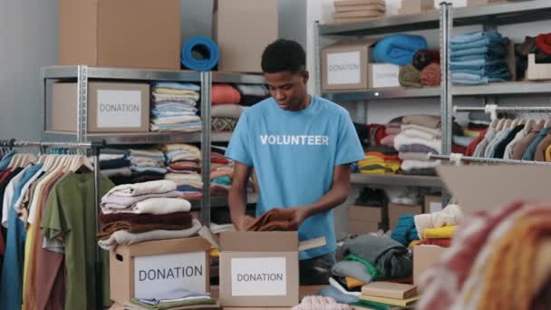 多人種男性ボランティアが衣類を分類し 倉庫の食器棚に入れます 人道支援と寄付の概念 — ストック動画