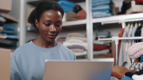 Multiracial Woman Sitting Laptop Working Second Hand Reuse Clothes Center — Stock Video