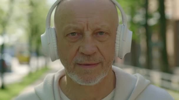 Porträt Des Lächelnden Reifen Mannes Mit Kopfhörern Der Auf Dem — Stockvideo