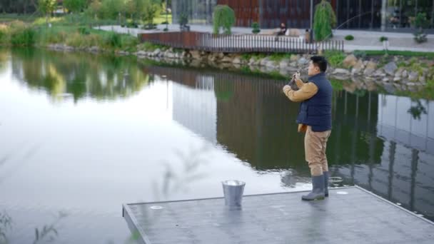 当天清晨 身穿特殊渔衣的亚洲男子在当地湖上的码头上抛出一根钓竿 体育捕鱼和人的概念 — 图库视频影像