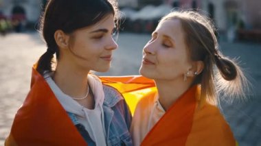 Igbt bayrağına sarılmış kameraya bakan lezbiyen bir çiftin portresi. Şehir merkezinde gökkuşağı bayrağıyla poz veren iki mutlu bayan arkadaş. Halkla ilişkiler konsepti