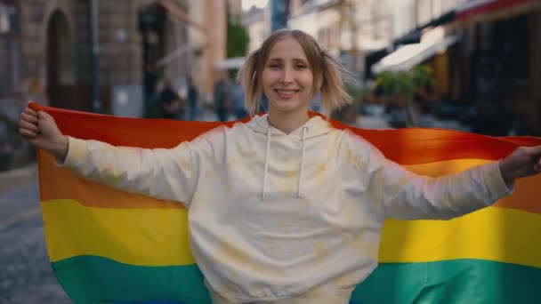 照片上 一个快乐的女人在看相机的时候 用大旗子盖住自己的肖像 站在城市街道上的千禧年女同性恋者的照片 自豪和男女同性恋 双性恋和变性者概念 — 图库视频影像