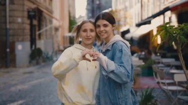 Portre seven lezbiyen kadınlar, sokakta birlikte dururlar, kalp hareketi gösterirler, el ele tutuşurlar, mutlu hissederler, aşık olurlar. Kadın ilişkileri, lgbt kavramı