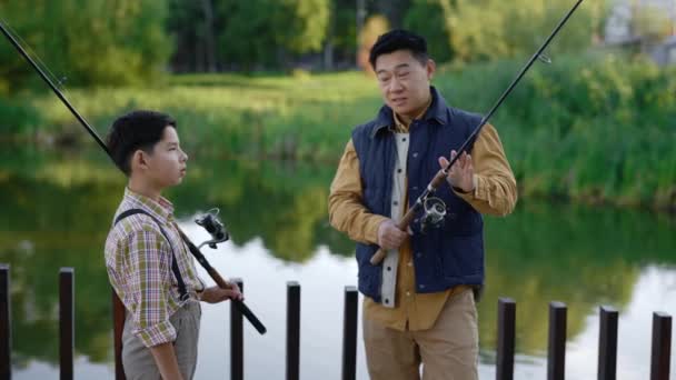 亚洲爸爸教他的儿子怎么扔钓竿 教他钓鱼 父亲告诉儿子如何正确地扔钓竿 家庭和父子关系概念 — 图库视频影像
