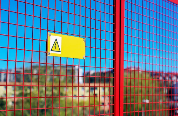 Polonya 'da bir yerlerde kırmızı ızgaradan sarkan yüksek voltaj uyarı levhası.