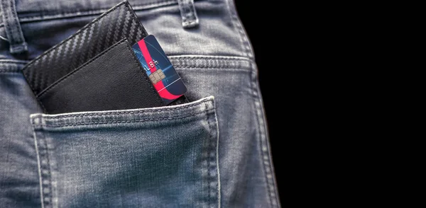 Credit card in the black wallet sticking out of the back pocket of the pants