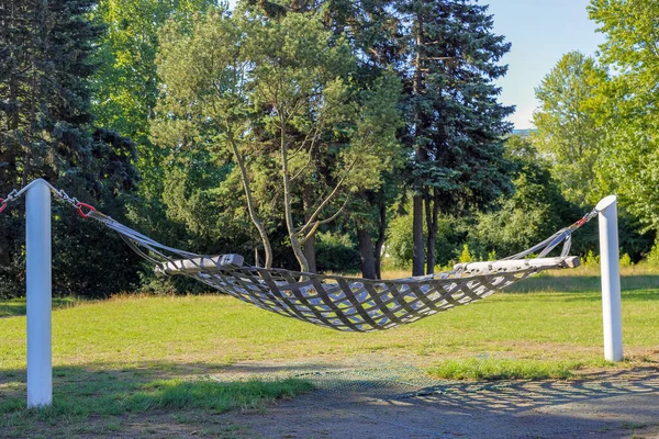 A hammock stretched over two white posts in a city park in Gdynia, Poland
