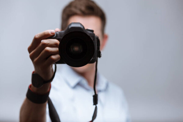 Photographer holding dslr camera on bright backround
