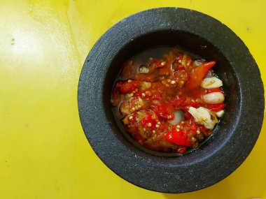 Sambal veya sambel korek veya setan veya peda veya cabai veya cabe veya geleneksel acı biber. Lumpang veya Lulumpang veya alat penumbuk veya cobek batu veya taş öğütücüsünde servis edilir. Endonezya 'nın ana menüsü için yan yemek