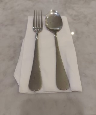 Bir çift kaşık ve çatal mermer bir masada beyaz bir doku üzerinde. Sekssel odaklanma. İzole edilmiş arkaplan