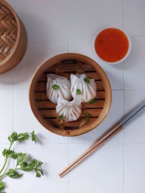 Seçici odak Hakau ya da şeffaf kabuklu Dim Sum dolu karides. Geleneksel Çin yemekleri. Bambu ahşap buharlı vapurda servis edilmiş. Biber sosu ve çubukla tamamlanmış. Kerevizle süslenmiş..