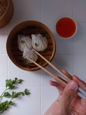 Seçici odak Hakau ya da şeffaf kabuklu Dim Sum dolu karides. Geleneksel Çin yemekleri. Bambu ahşap buharlı vapurda servis edilmiş. Biber sosu ve çubukla tamamlanmış. Kerevizle süslenmiş..