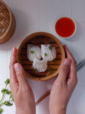 Seçici odak Hakau ya da şeffaf kabuklu Dim Sum dolu karides. Geleneksel Çin yemekleri. Bambu ahşap buharlı vapurda servis edilmiş. Biber sosu ve çubukla tamamlanmış. Kerevizle süslenmiş..