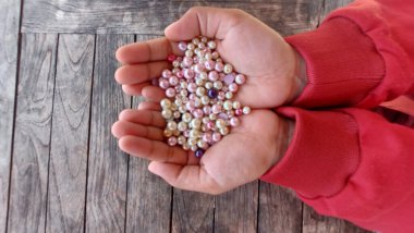 Yapay inciyi tutan bir kadın eli.