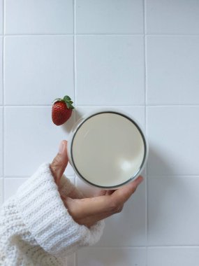 Bir bardak süt. Çilekle tamamlanmış. Beyazlar içinde izole edilmiş bir arka plan. Asgari fotoğrafçılık konsepti.