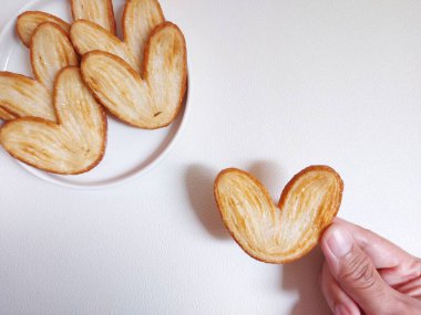 Orijinal turta bisküvileri ya da poğaça, fil kulağı ya da Fransız kalbi kurabiyesi ya da poğaça, bal, çift fırıldak ya da kelebek kurabiyelerinden yapılmış palmier bisküvi. Beyaz tabakta servis edilir..
