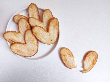 Orijinal turta bisküvileri ya da poğaça, fil kulağı ya da Fransız kalbi kurabiyesi ya da poğaça, bal, çift fırıldak ya da kelebek kurabiyelerinden yapılmış palmier bisküvi. Beyaz tabakta servis edilir..