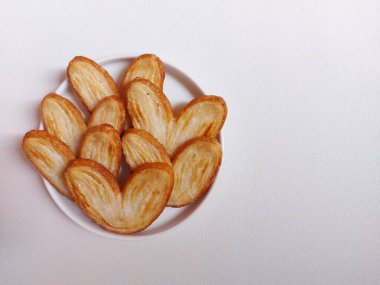 Orijinal turta bisküvileri ya da poğaça, fil kulağı ya da Fransız kalbi kurabiyesi ya da poğaça, bal, çift fırıldak ya da kelebek kurabiyelerinden yapılmış palmier bisküvi. Beyaz tabakta servis edilir..