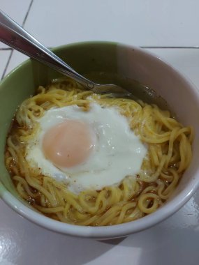 Kaynamış şehriye çorbası ve yarım haşlanmış yumurta. kaşık ve çatalla tamamlandı.