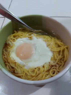 Kaynamış şehriye çorbası ve yarım haşlanmış yumurta. kaşık ve çatalla tamamlandı.