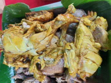 Sarı baharatlı kızarmış tavuk pişmeye hazır. Muz yaprağında servis. Endonezya geleneksel yemekleri.
