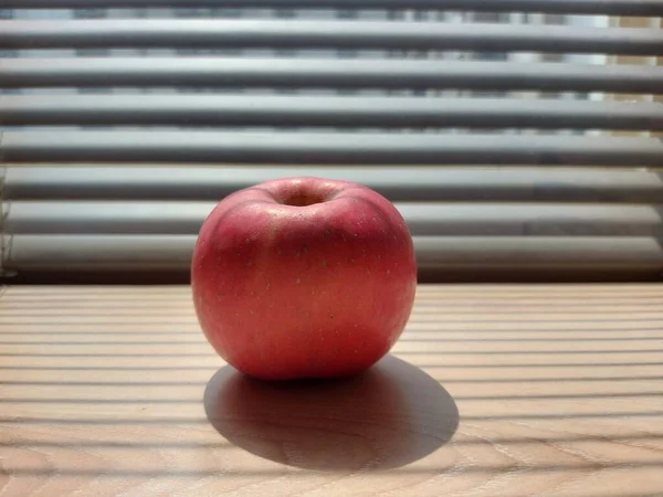 Czerwone Jabłko Brązowym Drewnianym Stole Wyposażone Dramatyczne Światło Cienia Rolet — Zdjęcie stockowe