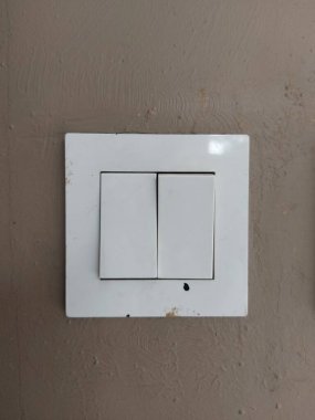 Duvardaki ışığı açıp kapatmak için beyaz elektrik düğmesi. Kahverengi arka planda. kopyalama alanı. Beyaz fotoğraf teması üzerine beyaz.