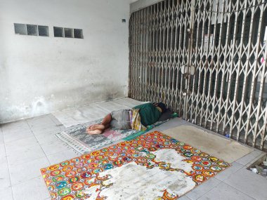 Jakarta, Endonezya - 26 Şubat 2022: Kapalı bir dükkanın önünde uyuyan zavallı evsiz adam