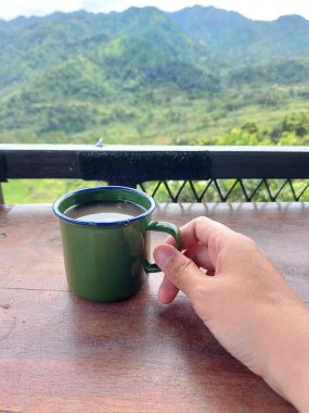 Kadınlar, yeşil diş minesi bardağında zencefilli ve bitkisel içecek tutuyor. Endonezya 'nın geleneksel içeceği. Bulanık tepe manzaralı. Çay saati konsepti