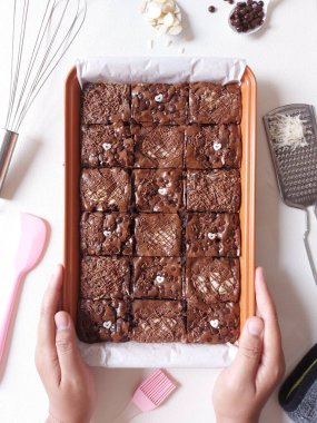 Fırında pişmiş çikolatalı kek. Peynir soslu, çikolata parçacıklı badem ve çikolata ezmeli. Fırça, peynir rendesi, fırça, spatula ve beyaz kaşıkla tamamlanmış. İzole edilmiş arkaplan beyaz.