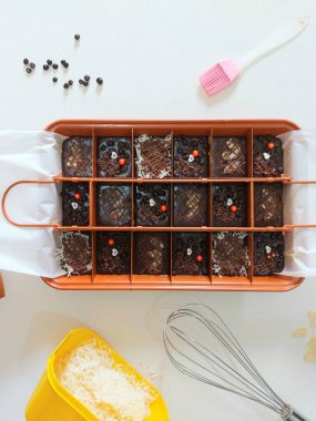 Fırında pişmiş çikolatalı kek. Peynir soslu, çikolata parçacıklı badem ve çikolata ezmeli. Fırça, peynir rendesi, fırça, spatula ve beyaz kaşıkla tamamlanmış. İzole edilmiş arkaplan beyaz.