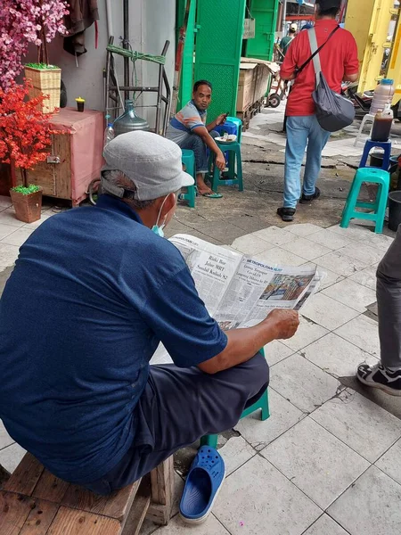 ジャカルタ インドネシア 2022年2月26日 歩行者天国の通りで新聞を読んで座っている帽子の男 — ストック写真