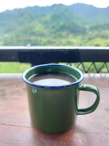 温热的姜汁香草饮料在绿色搪瓷杯上 印度尼西亚的传统饮料 山景朦胧 茶点时间概念 — 图库照片