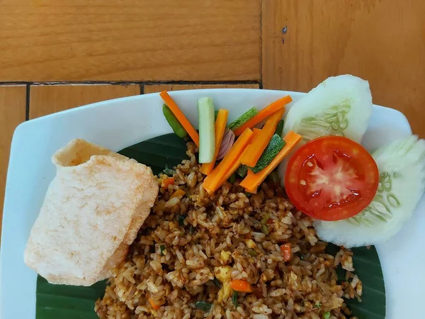 Fried rice or nasi goreng is a typical food from Indonesia which is usually served at breakfast or dinner. complete with carrot, tomato and cucumber. Also crackers. top view.