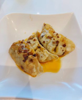 Gyoza ya da kızarmış hamur köftesi. Biber yağıyla tamamlanmış. Geleneksel Çin yemekleri